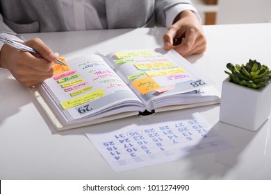 Close-up Of A Businesswoman Making Agenda On Personal Organizer At Workplace - Powered by Shutterstock