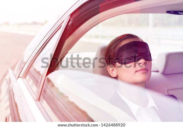 Closeup of\
businesswoman napping with mask in\
car