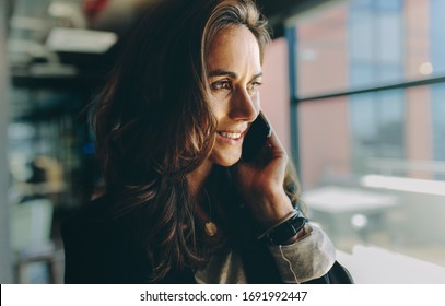 Close-up Of A Businesswoman Using Mobile Phone And Smiling. Female Executive Talking On A Phone In Office.