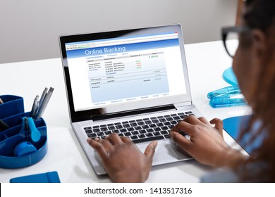 Close-up Of A Businesswoman's Hand Doing Online Banking On Laptop Over White Desk