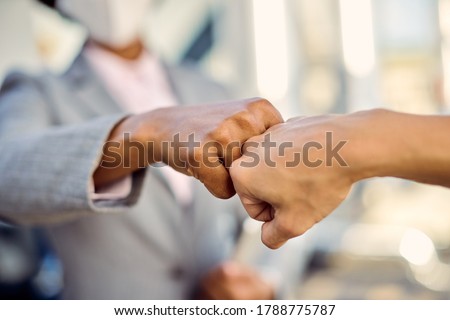 Close-up of businesswomen fist bumping while greeting during coronavirus pandemic.