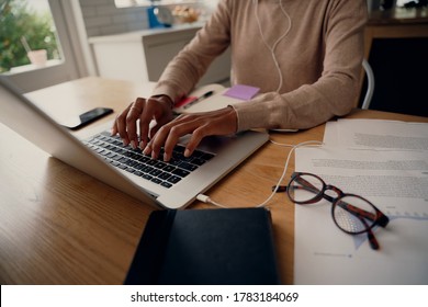 Close-up of busy female hand typing on keyboard while sitting at her home with documents and eyeglasses