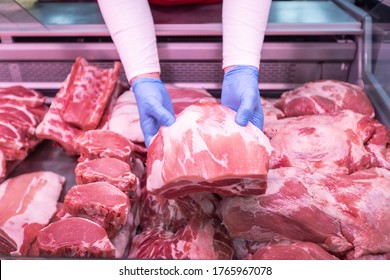 Closeup of butcher's hands holding meat piece. Offering fresh meat at display in supermarket - Powered by Shutterstock