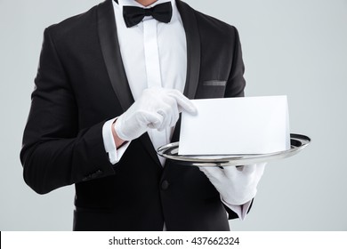 Closeup of butler in tuxedo and gloves holding blank card on tray