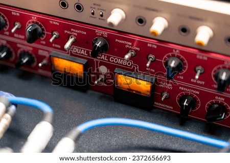 close-up of buttons and control system of a red microphone preamplifier in a recording music studio