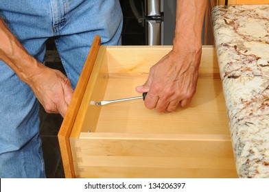 Closeup Of A Cabinet Installer Installing Drawer Hardware On New Kitchen Cabinets. Horizontal Format, Man Is Unrecognizable.