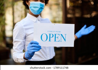 Close-up of cafe owner holding open sign while reopening during coronavirus epidemic. - Powered by Shutterstock