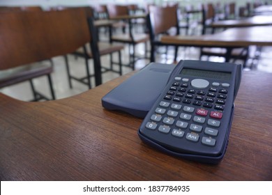 Close-up of calculator on the wood lecture chairs place distancing in the empty classroom. Back to school, business, and finance accounting concept.