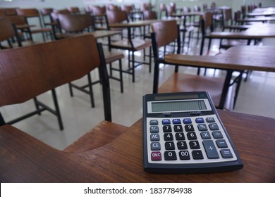 Close-up of calculator on the wood lecture chairs place distancing in the empty classroom. Back to school, business, and finance accounting concept.