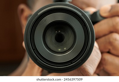 Close-up of a camera lens held by a photographer - Powered by Shutterstock