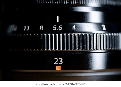Close-up of a camera lens showing the aperture and focal length settings. The aperture ring is set to f5.6 and the focal length is 23mm.