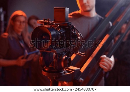 Closeup of cameraman operating video camera on rig in studio with red neon lights copy space
