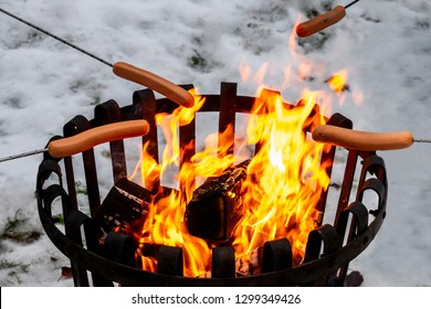 Closeup of a campfire with hot dog food over open fire. Winter snow outdoor scene. - Powered by Shutterstock