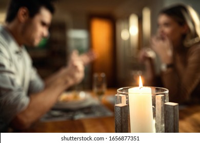 Close-up of candlelight on dining table with couple in the background. 