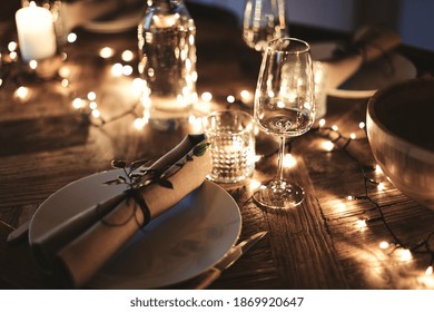 Closeup of a candlelit dining table set up with wineglasses and tableware for an evening dinner party