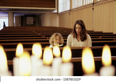 Closeup of candles lit with woman and child praying in Munich Arkivfotografi