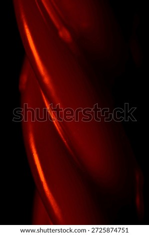 Close-up of the candle's surface. The slenderness and purity of the wax create an elegant visual effect in shades of red. Vertical view.