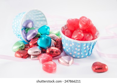 Closeup Of Candy, Foil Wrapped Chocolate Hearts, Ribbon, Valentines Hearts On A White Background 