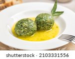 Close-up of canederli with spinach served in soup - bread dumplings made from dried bread rolls, milk, spinach, cheese and eggs. Trentino food, Italy. Selective focus.