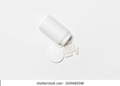 Closeup Capsules falling from white white Bottle on white background.Pills and pill Bottle Mock-up.High resolution photo.Top view
