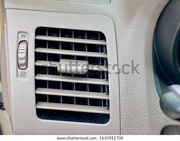Closeup of car air conditioning\
ventilation opening and dial to control air flow from\
vent.