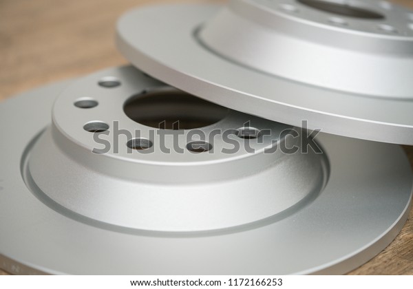Close-up of car brake disc / rotor on a\
wooden table with soft-focus in the background.\
