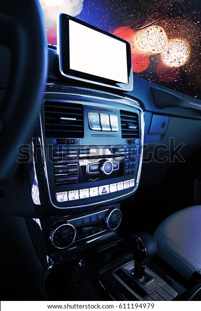 Closeup of car dasboard with radio, climate\
control and navigation device with empty screen. Car driving on the\
street with bokeh in\
background