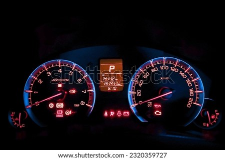 Close-up of car dashboard showing indicator light icon before starting engine. The car dashboard displays colorful symbols at night when the engine is started.
