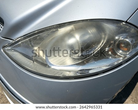 Close-up of a car headlight with cloudy, oxidized plastic lens, showing reduced clarity and light output due to aging and UV exposure.