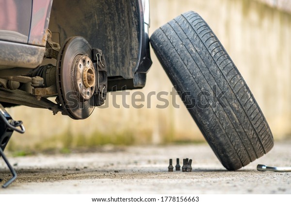 Closeup of a car\
lifted on jack in process of new wheel tire replacement. Breakdown\
of a vehicle on a\
street.