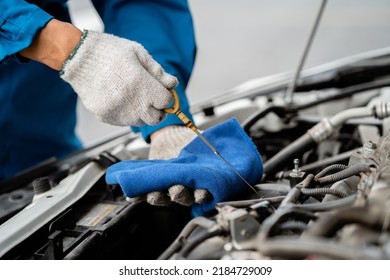 Close-up, a car mechanic checking the oil in a car's engine. Technician inspecting and maintaining the engine of a car or vehicle. Female car mechanic checking car engine - Powered by Shutterstock