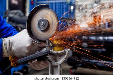 A close-up of a car mechanic using a metal grinder to cut a car silent block in a vise in an auto repair shop, bright flashes flying in different directions, in the background tools for an auto repair - Powered by Shutterstock