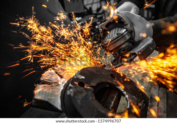 A
close-up of a car mechanic using a metal grinder to cut a brake
disk  in an auto repair shop, bright flashes flying in different
directions, in the background tools for an auto
repair