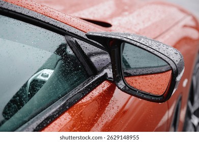 close-up car side mirror on rainy day showcases detailed raindrop texture on sleek red surface. modern automotive design highlights stylish aesthetics and weather resilience.