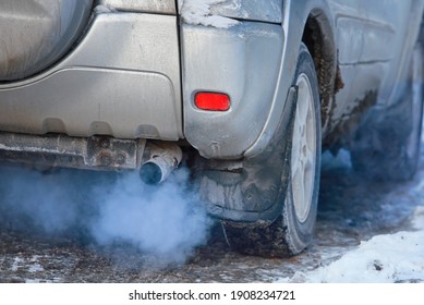 Close-up Of Car Smoking Exhaust Pipe, Car With Gasoline Engine. Gasoline Engine Warming Up At Idle In Winter Season. Blue Exhaust Smoke