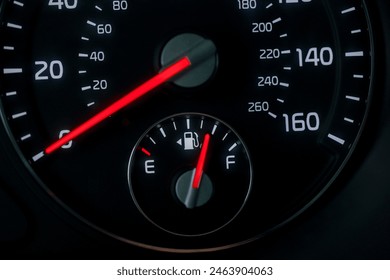 Close-up of a car speedometer and fuel gauge with vibrant red needles indicating speed and fuel level on a dark background. - Powered by Shutterstock