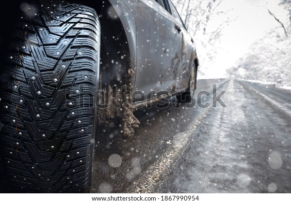 Closeup of car spikes  tires in winter on the\
road covered with snow. ice on the\
road