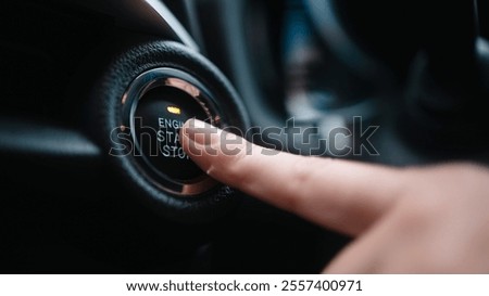 Close-up of a car start button being pressed by a woman. Concept of modern technology, convenience, and innovation in cars.