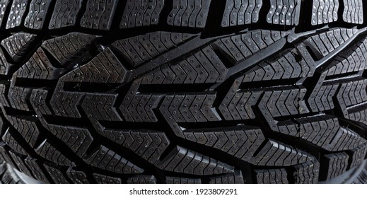 Closeup car tire isolated on black background. Wet with drops wheel against black