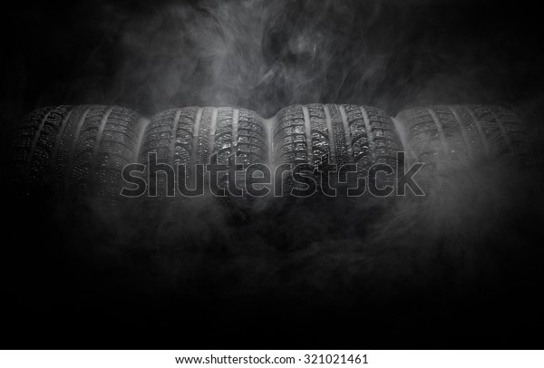 Close-up of\
car tires with smoke over black\
background