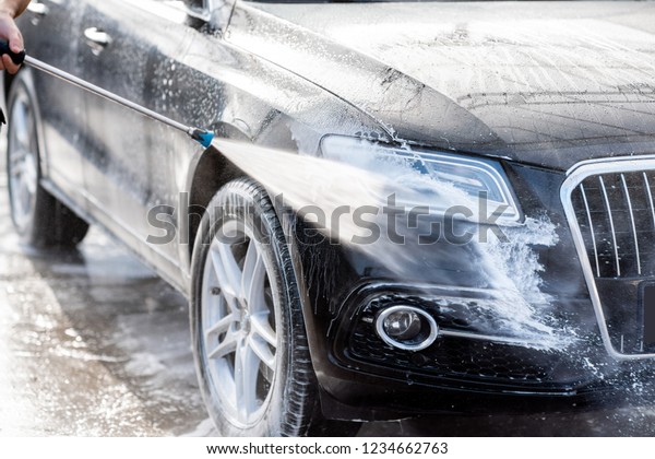 Close-up of a car under the water jet\
during the washing process on a self service car\
wash