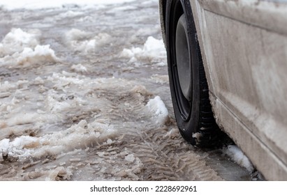 Close-up car wheel against the background of melting dirty snow - Shutterstock ID 2228692961