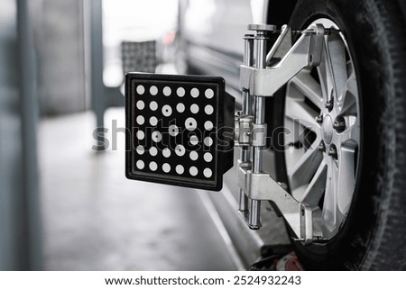 Close-up of a car wheel alignment process using advanced equipment in an automotive repair shop. Precise calibration for optimal vehicle performance.