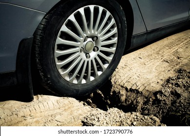 Close-up Of A Car Wheel Stuck In A Pit. Big Ditch On A Rural Road.Side View