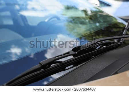 Close-up of car windshield wiper with reflections