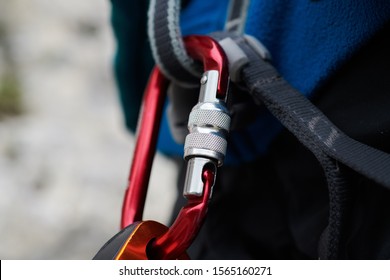 Close-up Carbine Of Rock Climber Wearing Safety Harness And Climbing Equipment Outdoor. Carabiner For Mountaineering. Equipment For Climbers. Carbine With A Large Load Capacity. Extreme Sport