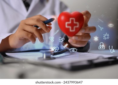 Closeup cardiologist holding red heart shape with virtual medical icons. Health care concept