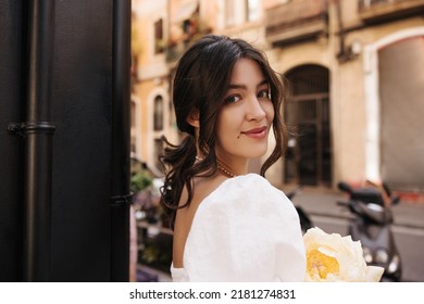 Close-up of carefree young caucasian woman looking at camera relaxing outdoors. Brunette in white summer clothes. Happy weekend concept. - Powered by Shutterstock