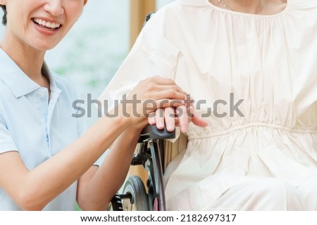 closeup of caregiver holding hands to woman in wheelchair