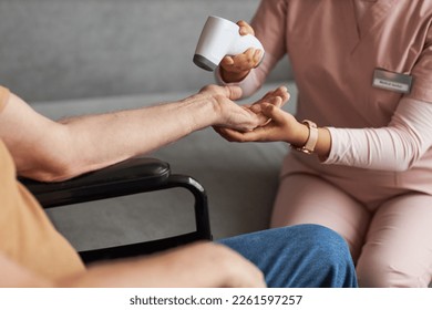 Close-up of caregiver in uniform holding arm of senior man and checking temperature with special medical equipment - Powered by Shutterstock